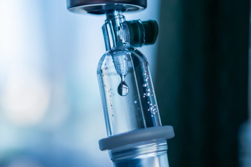 Close-up of a medical intravenous (IV) drip in a hospital setting.